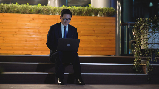 4k夜景商务男性坐在台阶上使用笔记本电脑视频