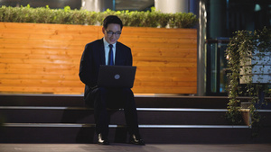 4k夜景商务男性坐在台阶上使用笔记本电脑21秒视频