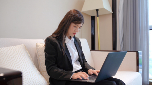 商务女性坐在沙发上使用笔记本电脑视频