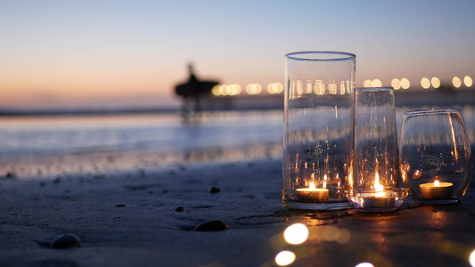 玻璃烛火海浪浪漫海滩约会夏日大海沙滩上的烛光视频
