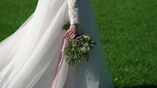 穿着结婚礼服的年轻新娘在公园里散步白色豪华礼服时装视频