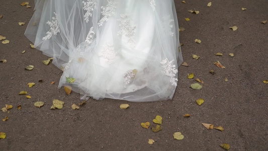穿着结婚礼服的年轻新娘在公园里散步白色豪华礼服时装视频