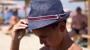 快乐的西班牙男孩在海滩上戴帽子笑着对镜头电影Dof16秒视频