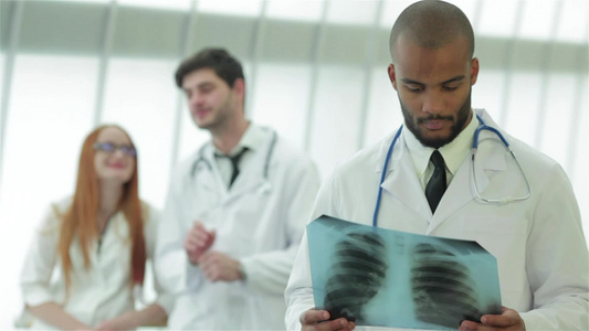 一位年轻医生的肖像照片两名同事的背景有X光片视频