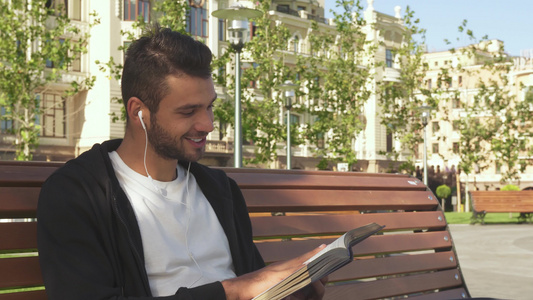 一个快乐的家伙正在读一本书在城市巷子里视频