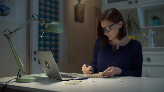 30多岁的年轻女性在家工作数着美元现金用钢笔做笔记视频
