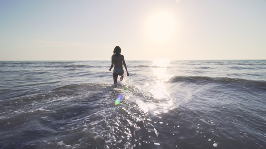 穿着比基尼的女孩在日落时在海中行走视频
