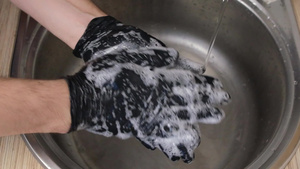 一个男人在水龙头下的水槽里用黑色橡胶手套洗手20秒视频