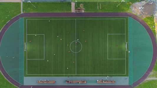 飞过绿色足球场中心球员们在踢足球空中垂直高视线视频