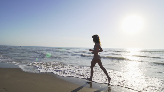 日落时穿着比基尼的女孩在海滩上奔跑视频