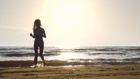 日落时在海滩上穿比基尼的女孩跳跃锻炼视频