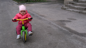 在街上骑三轮车的幼儿女孩慢动作17秒视频