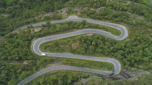 白色房车正在挪威蜿蜒的道路上行驶绿色森林空中垂直俯视图视频