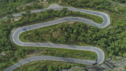 蓝色汽车在夏日在挪威山区蜿蜒的道路上行驶绿色森林空中视频
