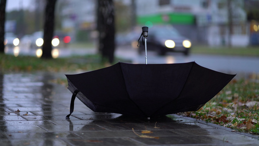 在雨季有人在路上投掷黑色雨伞视频