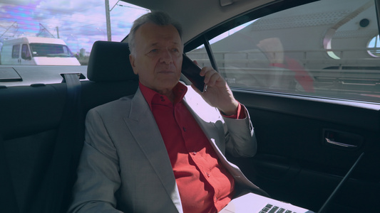 商人在汽车中使用移动电话和计算机视频