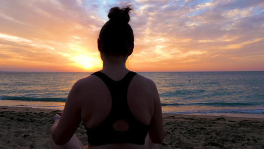 坐在沙滩上练瑜伽的女人夕阳剪影视频
