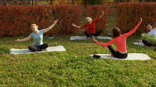 坐在床垫上和在公园做瑜伽的运动妇女视频