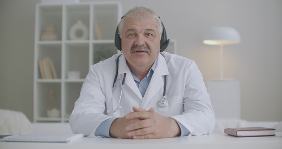 男性心脏病医生在网上咨询坐在诊所办公室用笔记本电脑视频