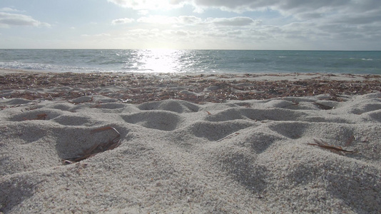 白石英沙粒的反光角度与海浪和背景中的云层天空相近视频