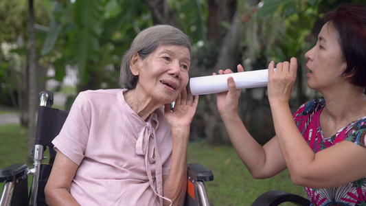 女儿用纸管与听力障碍的老年妇女交谈a使用纸管视频