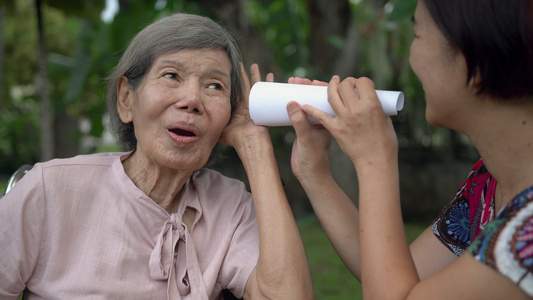 女儿用纸管与听力障碍的老年妇女交谈a使用纸管视频