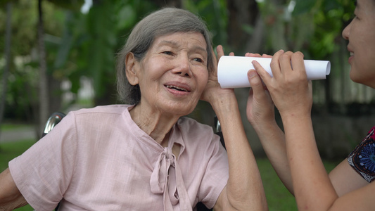 女儿用纸管与听力障碍的老年妇女交谈a使用纸管视频