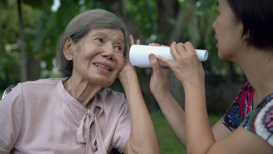 女儿用纸管与听力障碍的老年妇女交谈a使用纸管视频