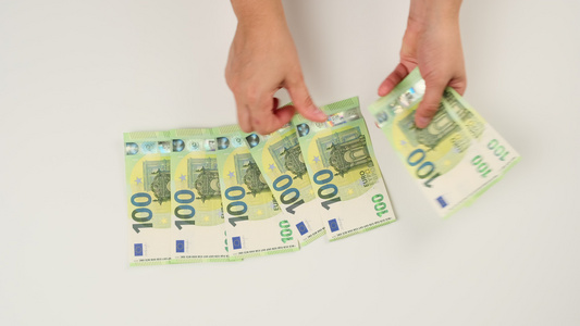 两只女性手在白色背景上数了一百欧元纸钞视频