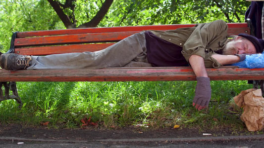 醉汉无家可归的男人白天睡在街上的长椅上笑声视频