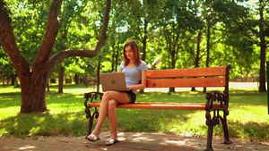 年轻妇女在坐在板凳上的电脑上打字16秒视频