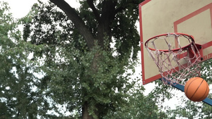 抛出橙色篮球在树荫下的户外法庭上击中篮子击中目标达到目标7秒视频