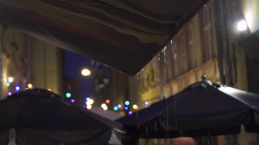 灯笼和彩色灯光挂起大雨滴落到欧洲老城狭窄街道的树冠视频