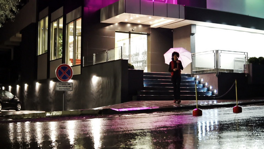 美丽的黑发美女雨夜带着雨伞行走视频