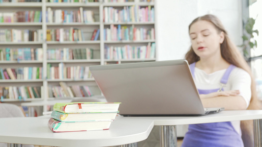 在背景上使用笔记本电脑的少女书籍中选取重点视频