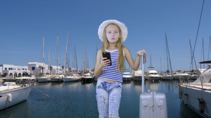 在游艇风景的海港携带旅行手提箱和移动电话的少女女孩15秒视频