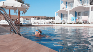 戴护目镜的少女在避暑胜地的游泳池水中游泳漂浮在度假村17秒视频
