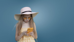 长头发的海滩型女孩在蓝背景下浏览手机以蓝背景浏览18秒视频