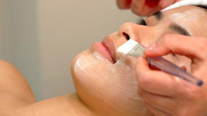 美容专家用刷子把化妆面罩套在女孩脸上14秒视频