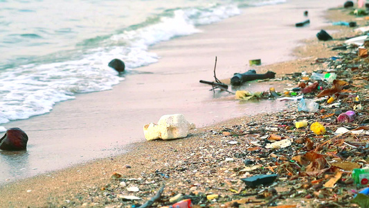 沙滩上留下塑料橡胶和废物海边日落海浪将它们吹入海中视频