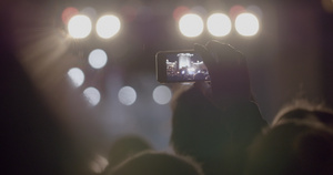 在户外音乐会上通过智能手机录制舞台在亮光聚光灯前的42秒视频