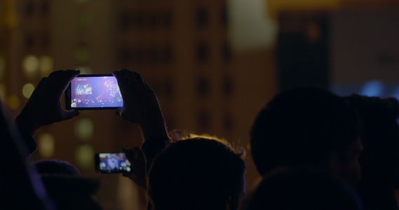 在户外音乐会通过智能手机录制带放大舞台和大屏幕的录像视频