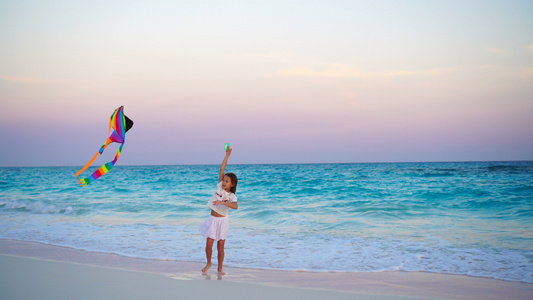 日落时在热带海滩放风筝的可爱小女孩孩子们在海边玩耍视频