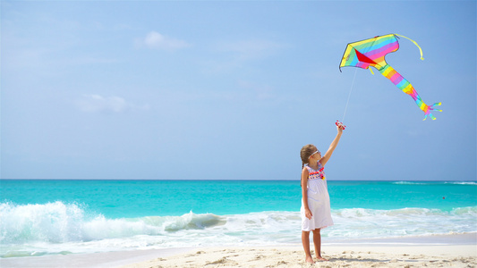 在热带海滩放风筝的小女孩孩子在海边玩耍有沙滩玩具的视频