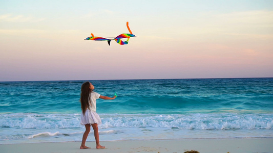 可爱的小女孩在热带海滩上放风筝快乐的孩子在海边玩着视频
