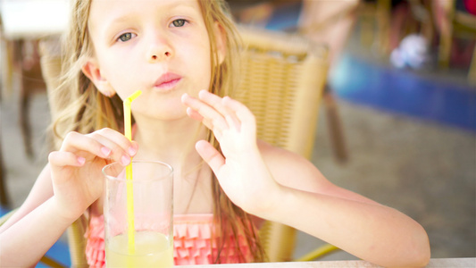 坐在晚餐桌边喝着新鲜果汁的可爱小女孩肖像视频