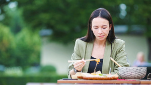 吃东西的年轻女人在户外餐桌吃面条17秒视频