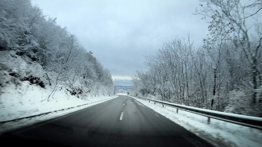 冬季乡村道路的汽车驾驶影片四周被雪包围挡风玻璃上有视频