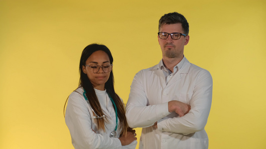 各种实验室大衣和眼镜的医生否认黄色背景的东西笑声视频