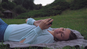 年轻女孩躺在公园的草坪上在手机上收到一条消息然后闭上眼睛11秒视频